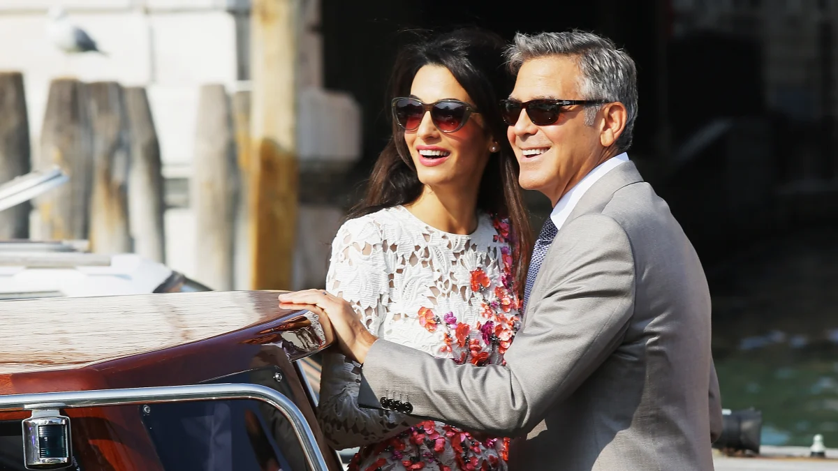 Amal Clooney and George Clooney stroll along Lake Como in a white feathered dress